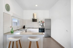 Une cuisine moderne dotée d’un îlot central, d’appareils électroménagers en acier inoxydable et d’une grande fenêtre.