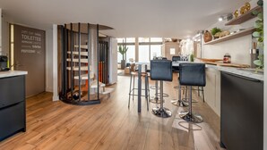 A modern kitchen with bar stools, a built-in stove, and a dining area with a view. - Holiday Home 'Beau Loft Lorient - Centre Ville' with Private Terrace and Wi-Fi (Lorient)