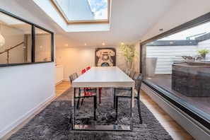 Un comedor moderno con tragaluz, una mesa grande, sillas y vistas al exterior.