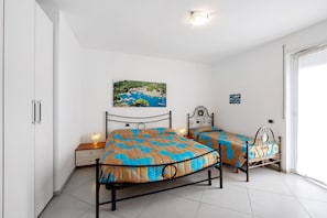 A bedroom with two beds, a nightstand, a wall-mounted picture, and a door leading to another room. - Apartment 'Frontemare' with Sea View, Wi-Fi and Air Conditioning (Savona)