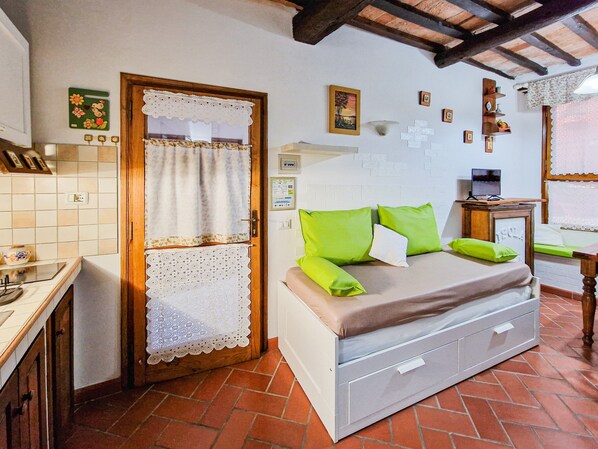 A bedroom with a bed, a desk, a chair, a window with a view, and a door with a curtain.