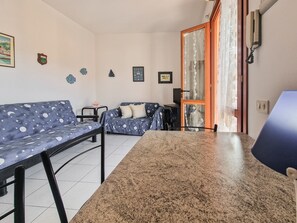 Een woonkamer met een bank, een bijzettafeltje en een televisie.