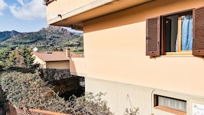 A building with a red-tiled roof, a balcony with a lattice fence, and a mountain backdrop.