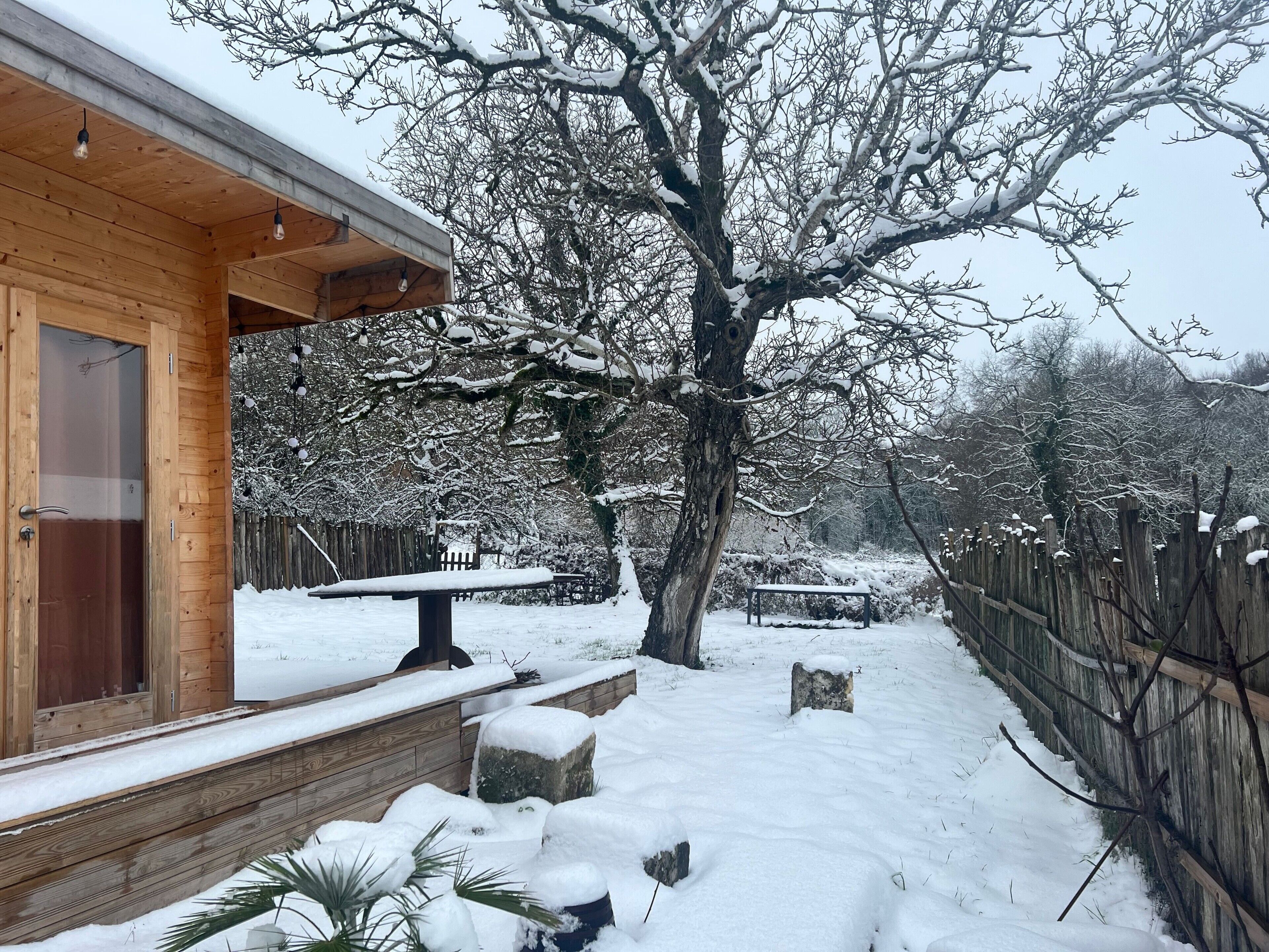 Une cabane en bois avec un porche couvert, un banc et un paysage enneigé.