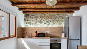 A kitchen with a stone wall, wooden ceiling, a microwave, a refrigerator, and a sink. - Vacation Home 'Casa Celestina' with Mountain View, Wi-Fi and Air Conditioning (Temisas)
