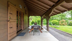 A covered outdoor dining area with a picnic table and chairs, wooden walls, and a view of greenery. - Chalet 'Indépendant 3 Personnes' with Mountain View, Private Terrace and Wi-Fi (Alex)