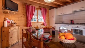 A wooden interior with a dining table, chairs, a television, and kitchen cabinets. - Chalet 'Indépendant 3 Personnes' with Mountain View, Private Terrace and Wi-Fi (Alex)