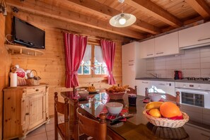 Um interior de madeira com uma mesa de jantar, cadeiras, uma televisão e armários de cozinha.