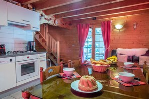 Interior de una cabaña de madera con cocina, mesa de comedor y una zona de estar acogedora.