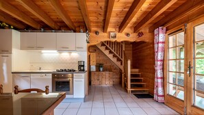 A wooden cabin interior with a kitchen, dining area, and staircase leading to a loft bedroom. - Chalet 'Indépendant 3 Personnes' with Mountain View, Private Terrace and Wi-Fi (Alex)