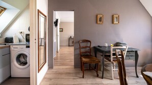 Un espace buanderie comprenant un lave-linge, une chaise, un bureau et deux tableaux encadrés accrochés au mur.