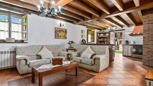 Una sala de estar con dos sofás, una mesa de centro y una cocina con pared de ladrillo y electrodomésticos.