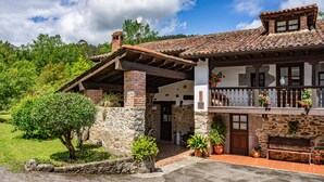 Una casa de piedra con balcón, un porche de madera y plantas en macetas.