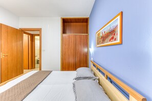A bedroom with a bed, wooden wardrobe, and a framed picture on the wall.