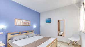 Ein Schlafzimmer mit einem Bett, Nachttischen, einem Sessel, einem Spiegel und zwei Wandleuchten.