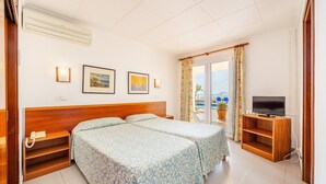 Une chambre d’hôtel avec deux lits, un meuble pour la télévision et une vue sur la mer.