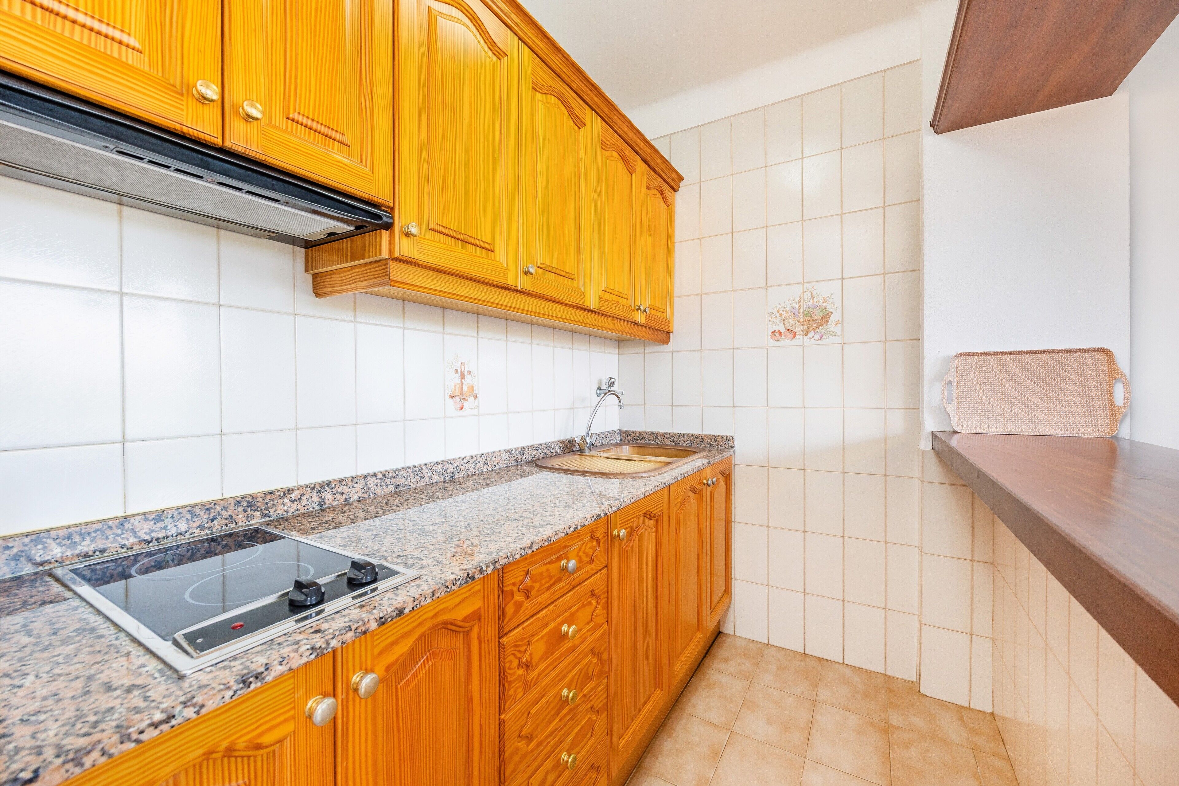 A kitchen with wooden cabinets, a granite countertop, a stainless steel sink, and a built-in stove.