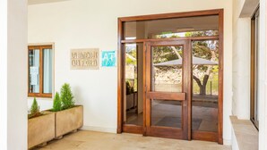 A wooden door with glass panels, a concrete planter with small plants, and a wall with two signs. - Apartment 'Vista Al Mar Y Vista Puerto' with Sea View, Wi-Fi and Air Conditioning (Cala Figuera)