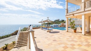 A pool area with lounge chairs, a staircase, and a view of the sea. - Apartment 'Vista Al Mar Y Vista Puerto' with Sea View, Wi-Fi and Air Conditioning (Cala Figuera)