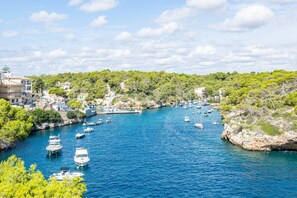 Un pueblo costero con barcos amarrados a lo largo de un canal estrecho, rodeado de vegetación y edificios.