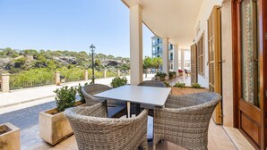 A balcony with wicker furniture, a table, and a view of a rocky landscape.