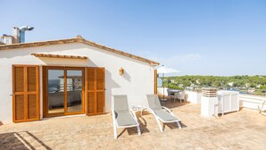 Una terrazza sul tetto con due poltrone, un tavolo e un ombrellone bianco.