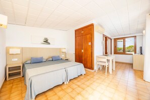 Een slaapkamer met een bed, nachtkastjes, een bureau en een kledingkast.