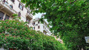 A multi-story building with balconies, surrounded by lush green trees and flowering shrubs. - Apartment 'Ohana Bnb' with Wi-Fi (Genova)