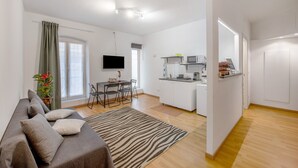 A modern living room with a sofa, a dining table, and a kitchen area with a microwave and cabinets. - Apartment 'Ohana Bnb' with Wi-Fi (Genova)