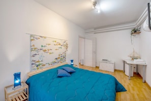 Une chambre à coucher comprenant un lit, une table de chevet, une commode, un bureau et un mur décoré d’un motif de poissons.