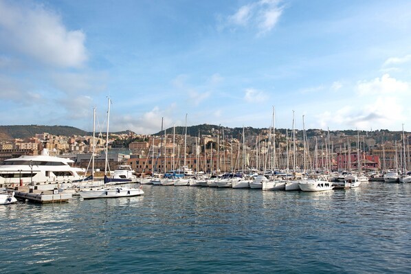 A marina with multiple boats docked, a large yacht, and a cityscape in the background.