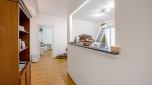 A hallway with a wooden cabinet, a desk with a plant, a chalkboard, and a window. - Apartment 'Ohana Bnb' with Wi-Fi (Genova)
