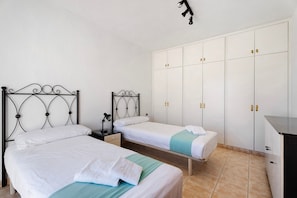 Une chambre avec deux lits, une armoire et un bureau.