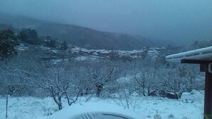 Paisaje nevado con vista a un pueblo y montañas a lo lejos.