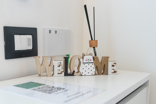 A reception desk with wooden letters spelling 'WELCOME,' a wall-mounted air purifier, and a reed diffuser. - Apartment 'La Dimora In Città' with Wi-Fi and Air Conditioning (Bari)