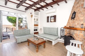 A cozy living room with a sofa, a coffee table, and a fireplace. - Vacation Home 'Kassiopea' with Private Pool, Private Terrace and Wi-Fi (Ciutadella de Menorca)