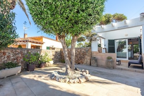 A courtyard with a tree, stone wall, and a building with a sign 'KASSIOPEA'. - Vacation Home 'Kassiopea' with Private Pool, Private Terrace and Wi-Fi (Ciutadella de Menorca)