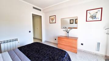 A bedroom with a bed, dresser, mirror, and artwork on the walls.