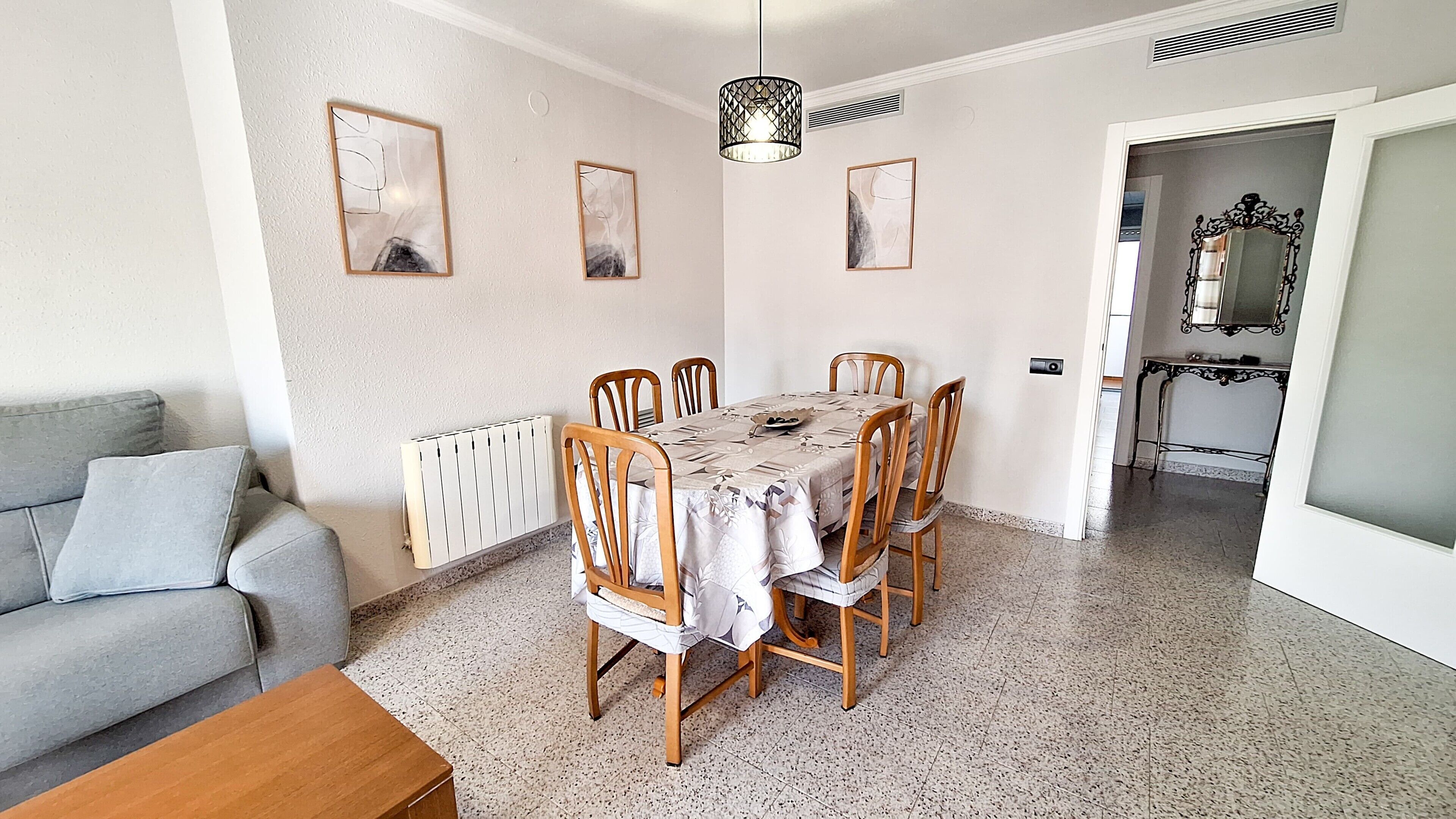 A dining area with a table, chairs, a radiator, and framed artwork on the walls.