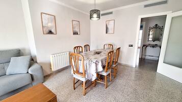 A dining area with a table, chairs, a radiator, and framed artwork on the walls.