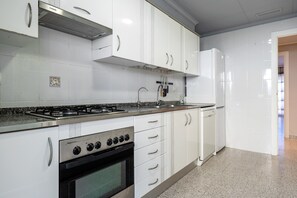 A kitchen with white cabinets, a gas stove, a built-in oven, and a refrigerator.
