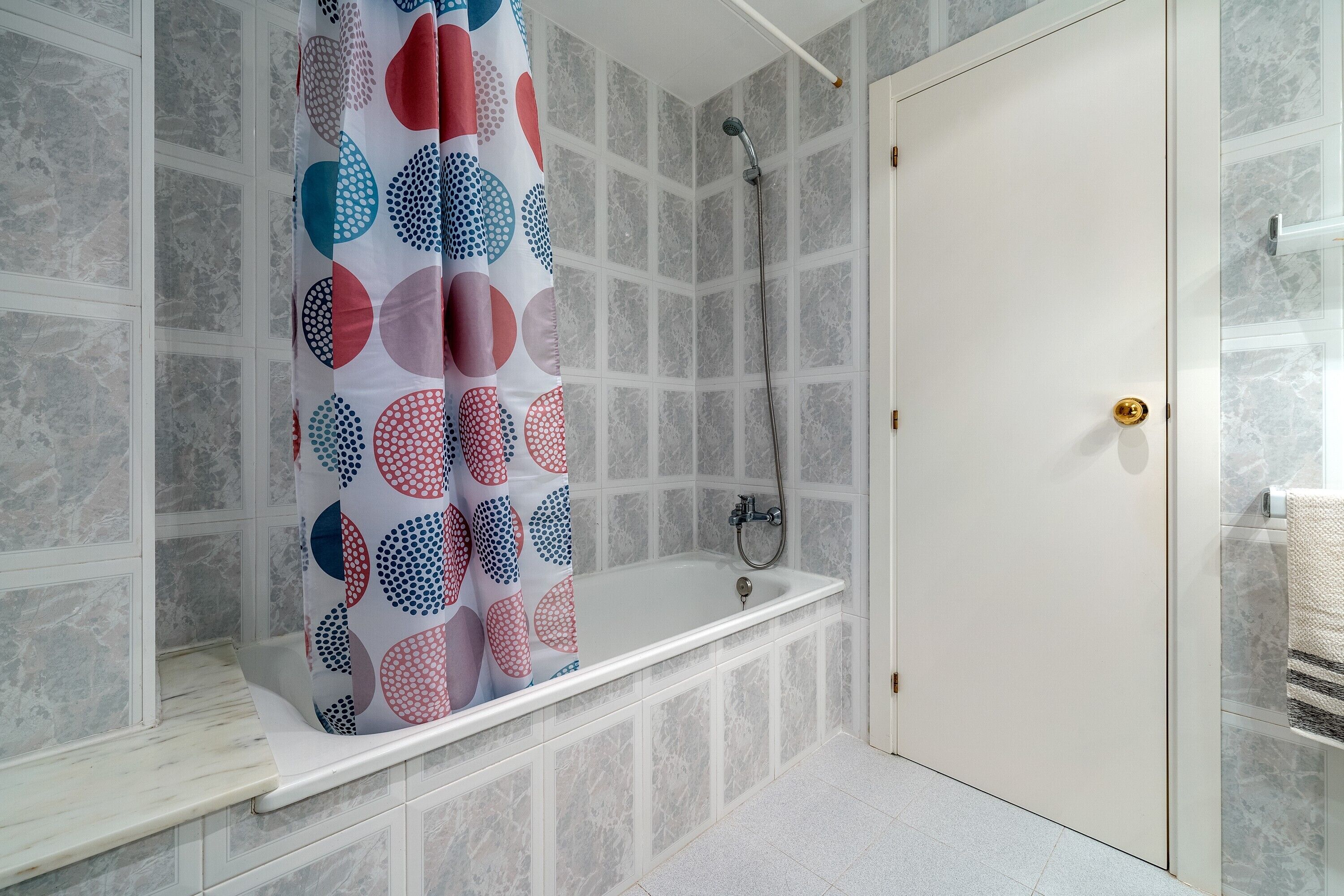 Une salle de bain avec une baignoire, une douche et une porte dotée d’une poignée dorée.