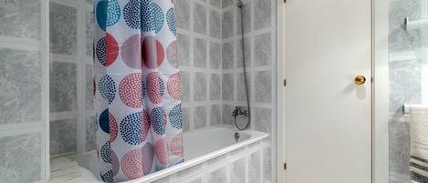 Une salle de bain avec une baignoire, une douche et une porte dotée d’une poignée dorée.