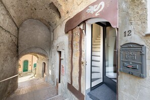 A narrow alleyway with a green door, a mailbox, and a staircase leading to an upper level. - Apartment 'Casa Gecko' with Mountain View, Private Terrace and Wi-Fi (Tovo San Giacomo)