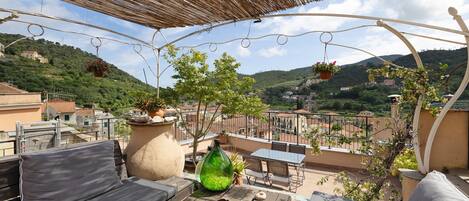 A terrace with a wooden table, a sofa, and hanging planters.