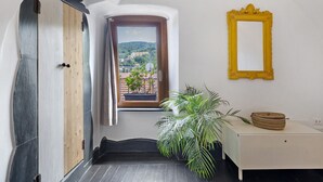 Una habitación con ventana, espejo, planta y puerta.