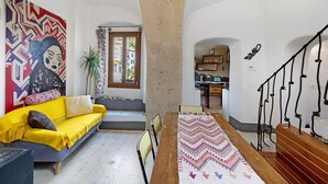 Una sala de estar con sofá, una mesa de comedor y una escalera.