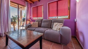 A room with a sofa, a table, and a window with a red blind.