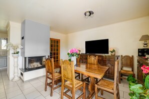 Un comedor con una mesa y sillas de madera, un televisor y una chimenea.