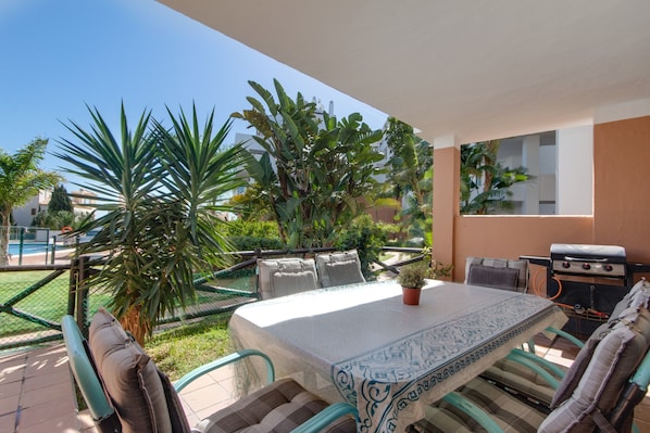 An outdoor patio with a table, chairs, and a grill.